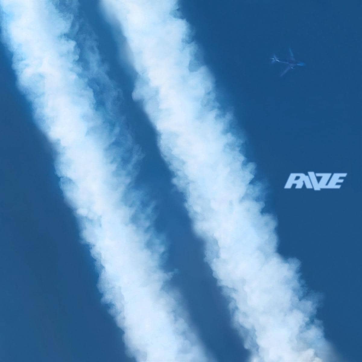 Pesawat terbang di langit biru meninggalkan dua jejak asap putih tebal dengan logo RIIZE di sisi kanan gambar.