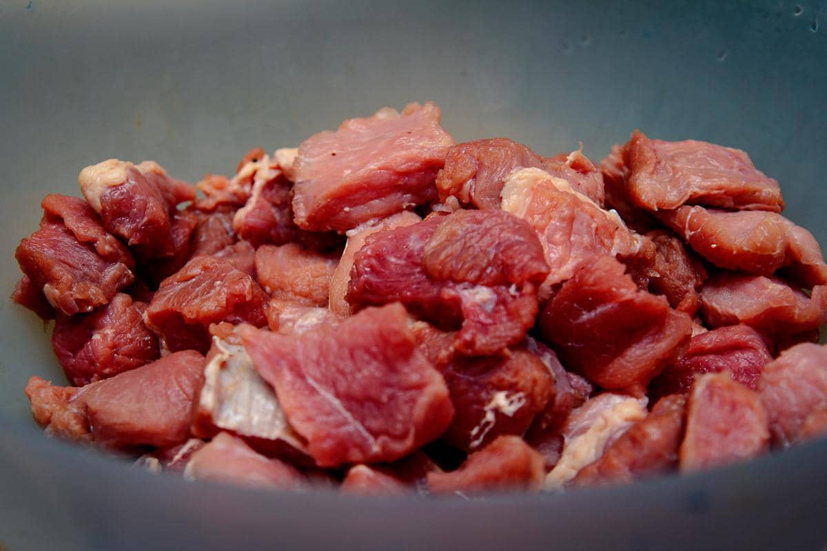 Potongan daging kambing mentah berwarna merah segar dalam wadah, siap diolah menjadi berbagai hidangan masakan.