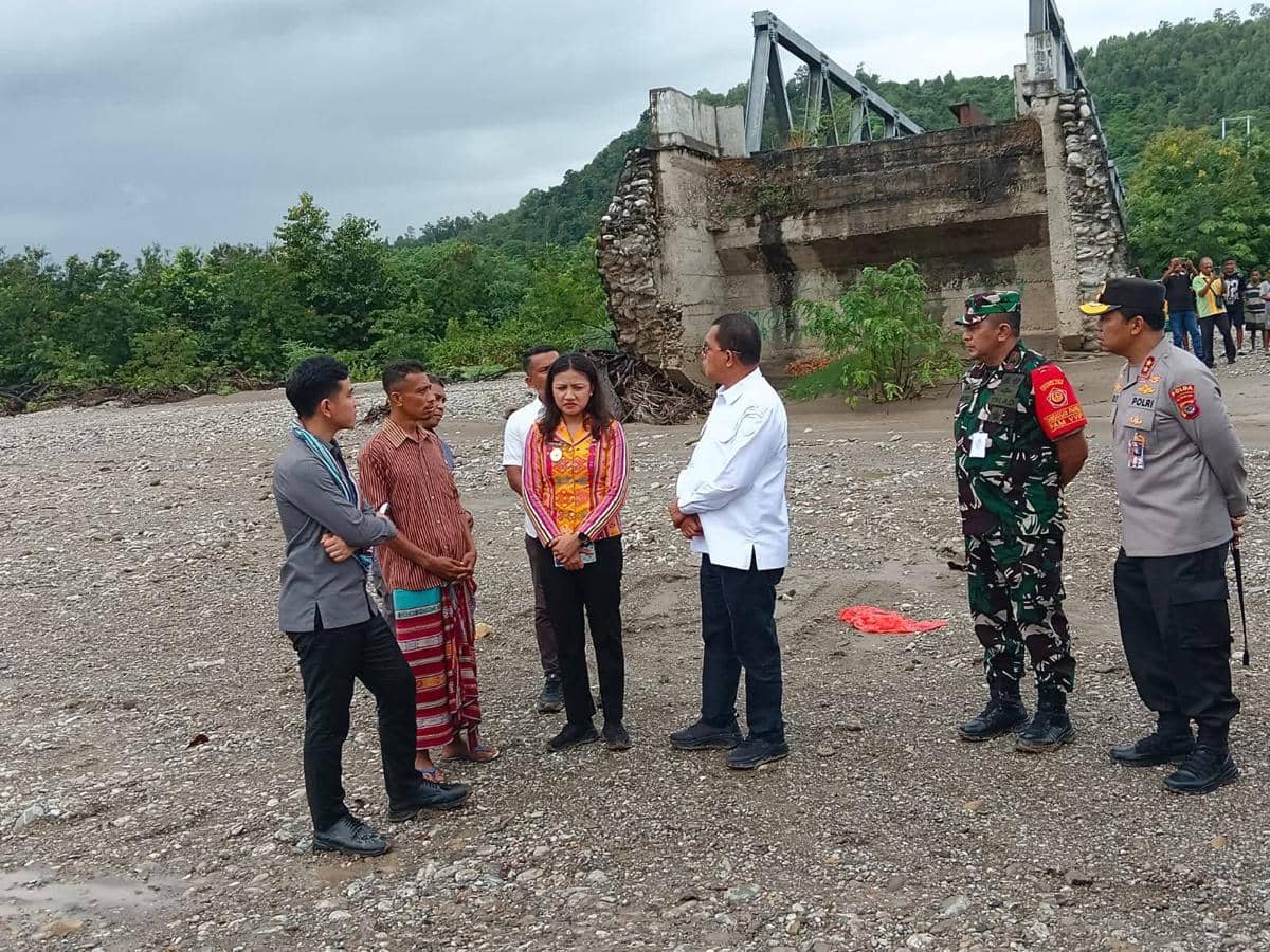 Sejumlah pejabat dan warga berdiskusi di dekat jembatan yang rusak di Amfoang, Kupang, Nusa Tenggara Timur, dengan latar pepohonan hijau.