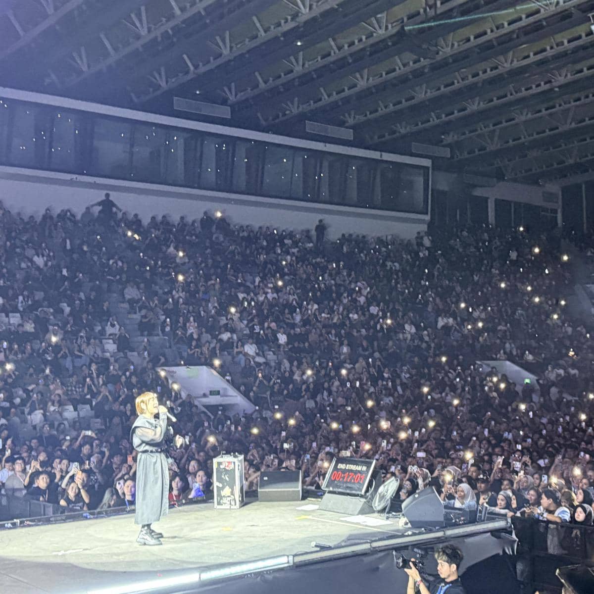 Seorang penyanyi tampil di atas panggung besar di depan penonton yang memenuhi arena konser di Jakarta dengan lampu ponsel menyala.