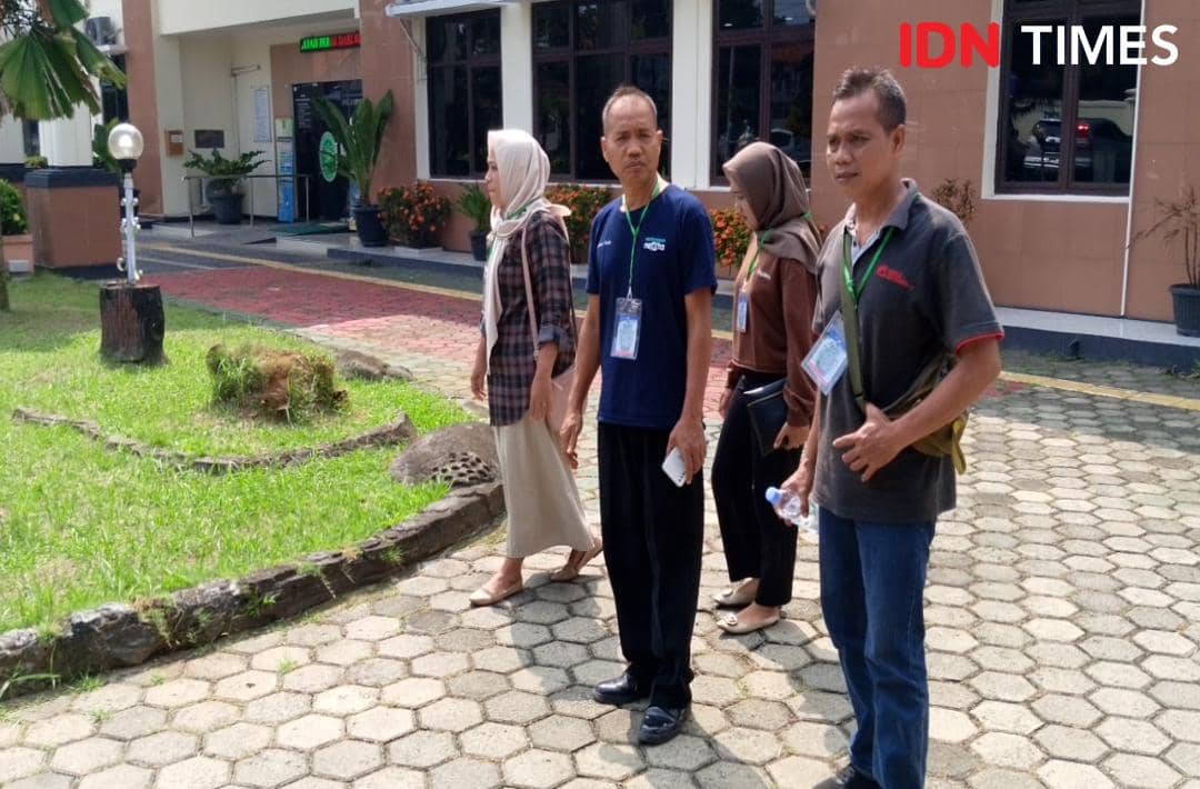 Empat orang keluarga korban berjalan di area luar gedung pengadilan dengan ekspresi serius dan mengenakan tanda pengenal.