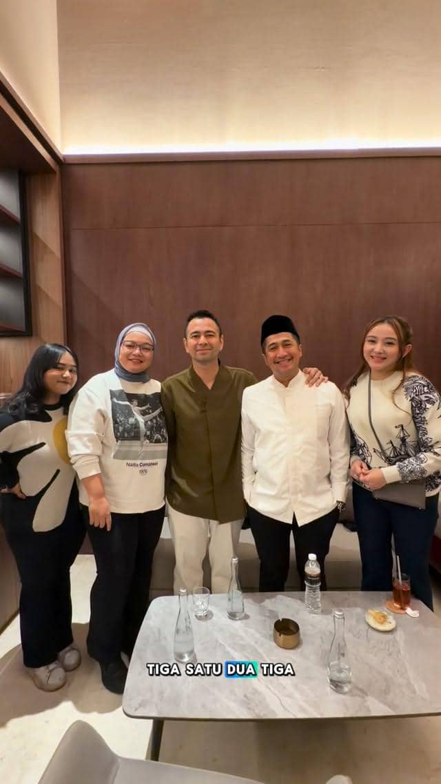 Lima orang berpose bersama di dalam ruangan dengan dinding kayu, berdiri di belakang meja dengan beberapa botol minuman dan gelas kosong.