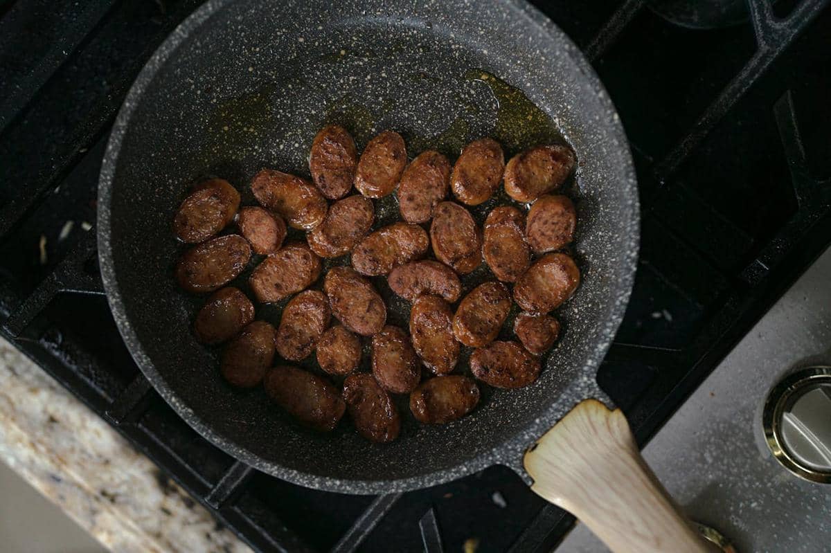 Potongan sosis darah Korea atau sundae sedang ditumis di wajan di atas kompor dengan sedikit minyak untuk membuat sundae bokkeum.