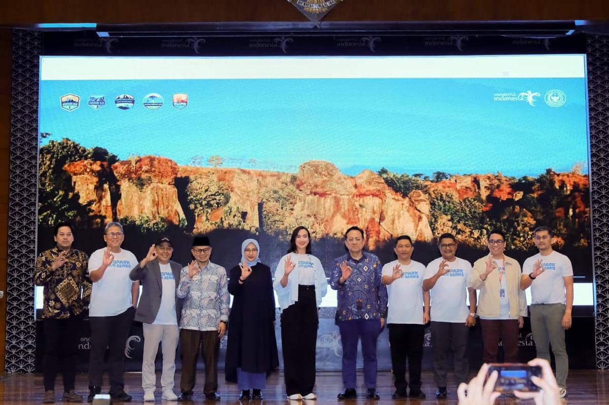 Sejumlah orang berpose di depan layar besar bergambar tebing batu merah dalam acara peluncuran Geopark Run Series 2026-2027.