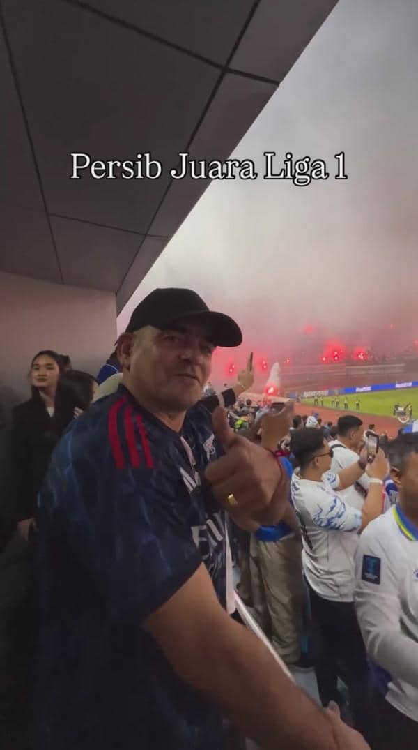Seorang pria mengenakan jersey biru memberi acungan jempol di stadion yang dipenuhi suporter Persib Bandung merayakan juara Liga 1.