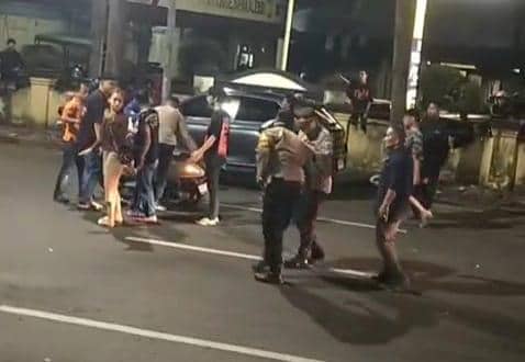 Beberapa petugas kepolisian dan warga berkumpul di jalan depan Mapolsek Ujung Pandang Makassar setelah insiden tabrakan saat razia malam.