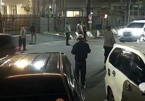 Petugas kepolisian melakukan razia keamanan di Jalan Hasanuddin, Makassar pada malam hari dengan beberapa kendaraan melintas di sekitar lokasi.