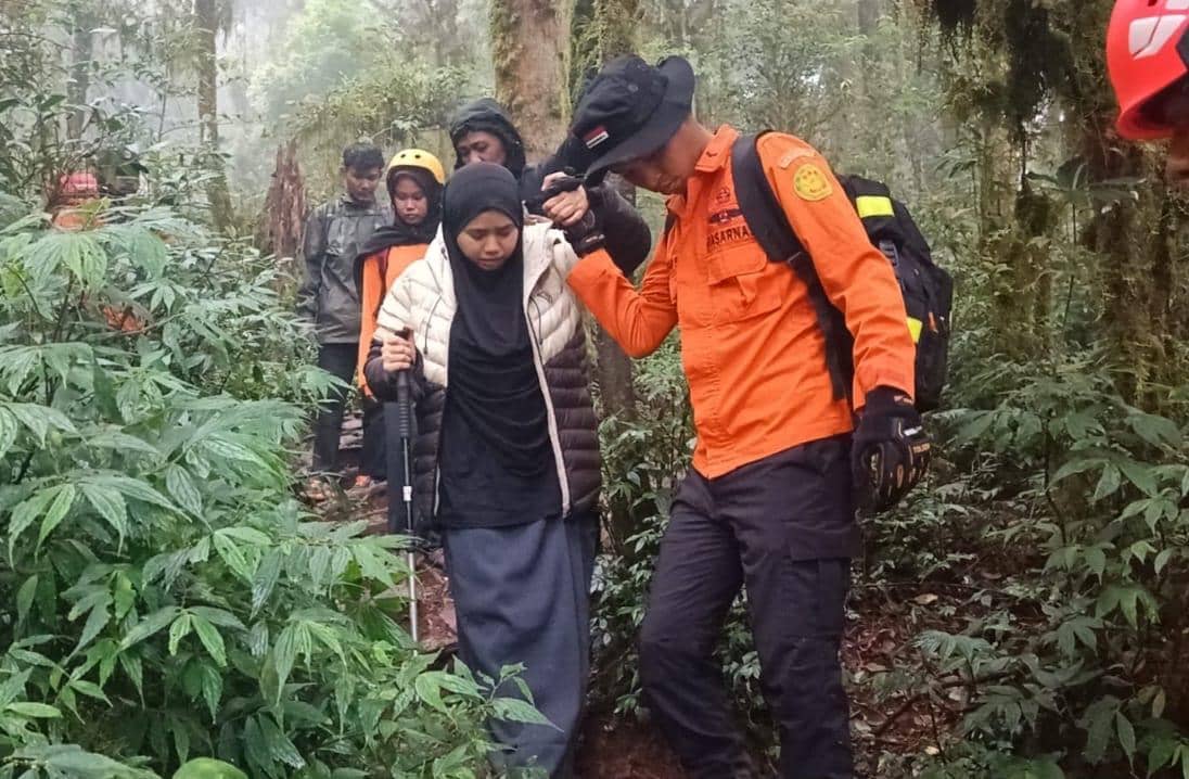 Petugas SAR membantu pendaki perempuan yang cedera saat evakuasi di jalur hutan Gunung Bulubaria dengan kondisi medan lembap dan berkabut.