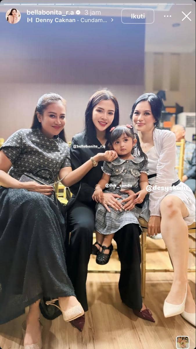 Tiga wanita berbusana elegan duduk bersama seorang anak kecil di acara pernikahan, tersenyum ke arah kamera di ruangan indoor.