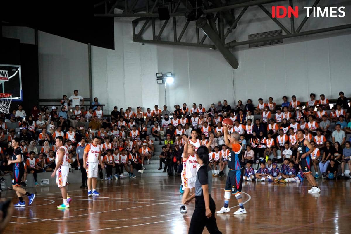 Pertandingan basket antara Timnas Legend dan UGM All Stars berlangsung di depan penonton yang memenuhi tribun dalam gedung olahraga.