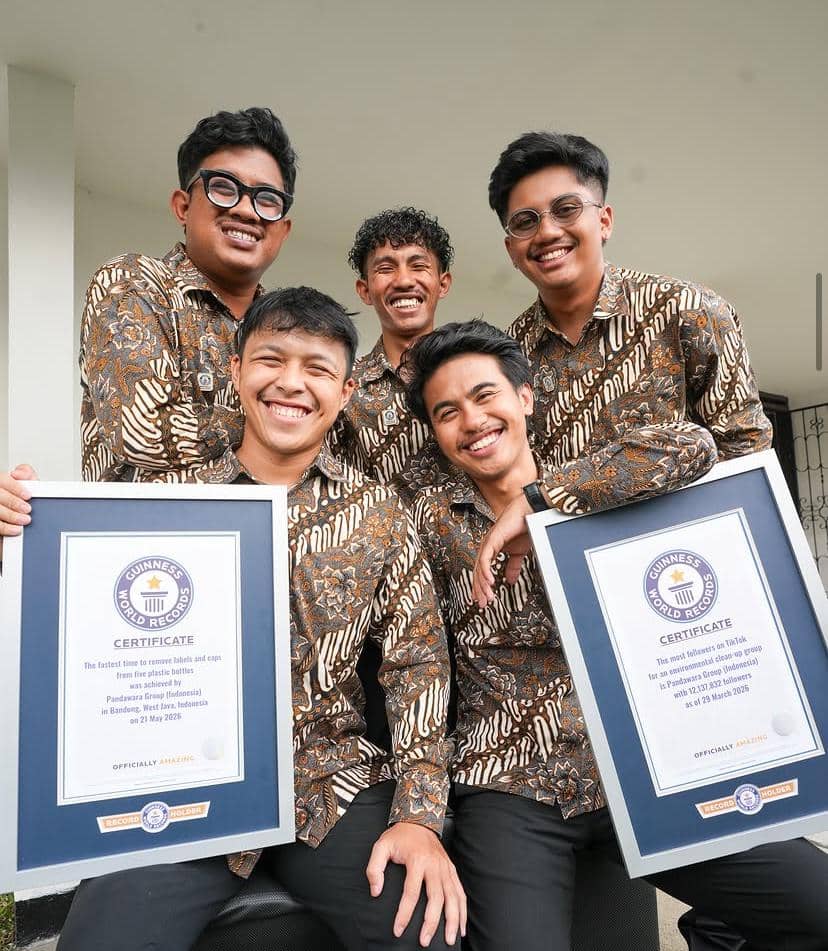 Lima pria mengenakan batik cokelat berpose sambil memegang sertifikat Guinness World Records di depan bangunan berwarna putih.
