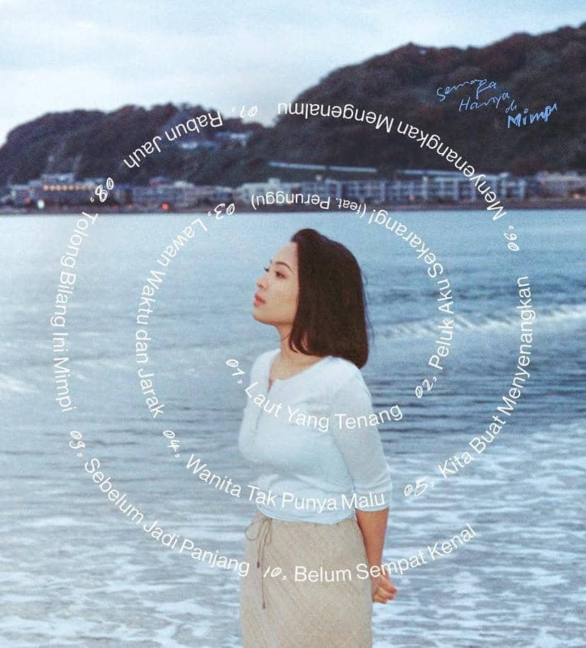 Seorang perempuan berdiri di tepi pantai dengan latar laut dan perbukitan, menampilkan daftar lagu album Semoga Hanya di Mimpi.
