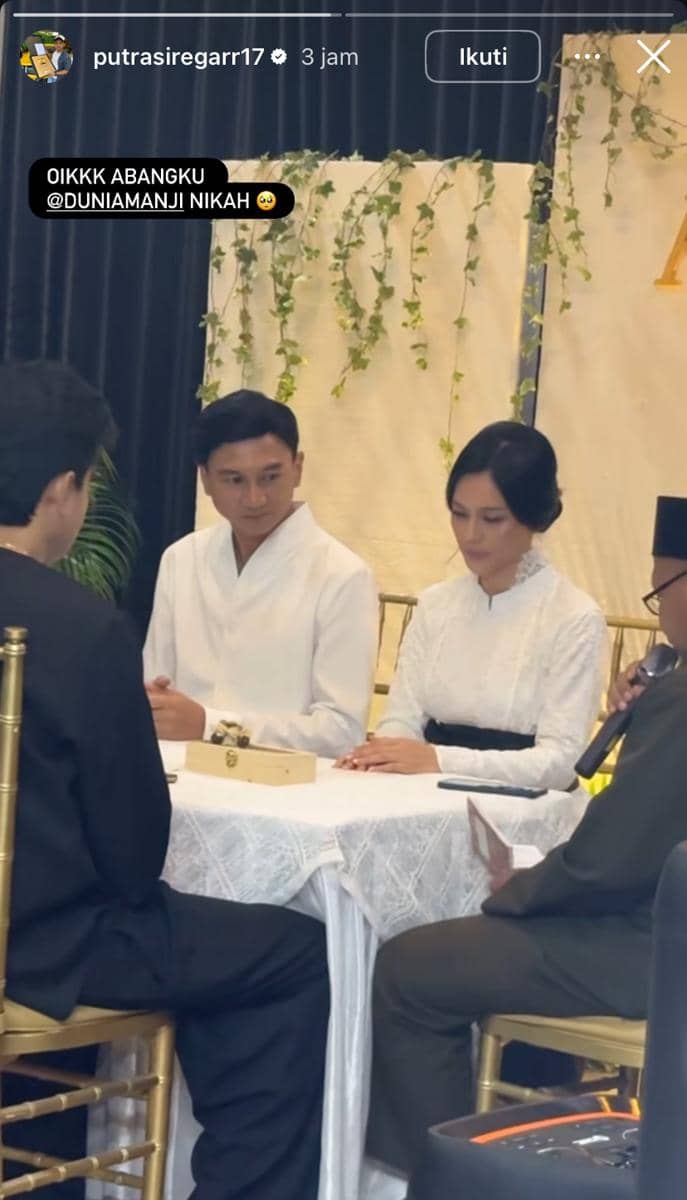 Pasangan pengantin duduk berdampingan mengenakan busana putih saat prosesi akad nikah di depan penghulu dan saksi.