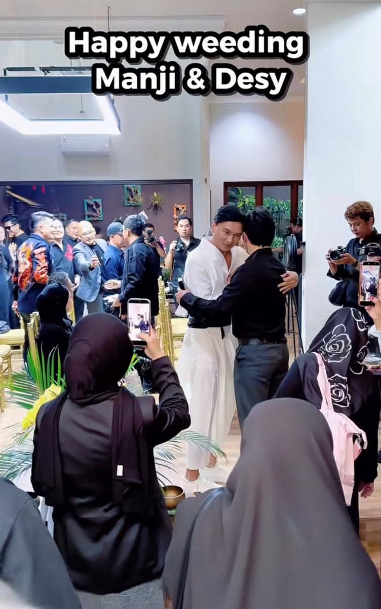 Suasana pernikahan Anji dan Desy dengan tamu undangan yang mengenakan busana formal, beberapa orang mengambil foto dan video momen tersebut.