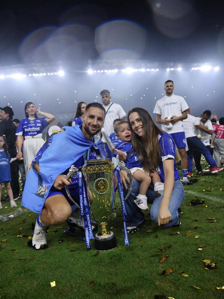 Pemain Persib Bandung berpose bersama keluarga dan trofi juara di lapangan stadion usai meraih gelar juara liga.
