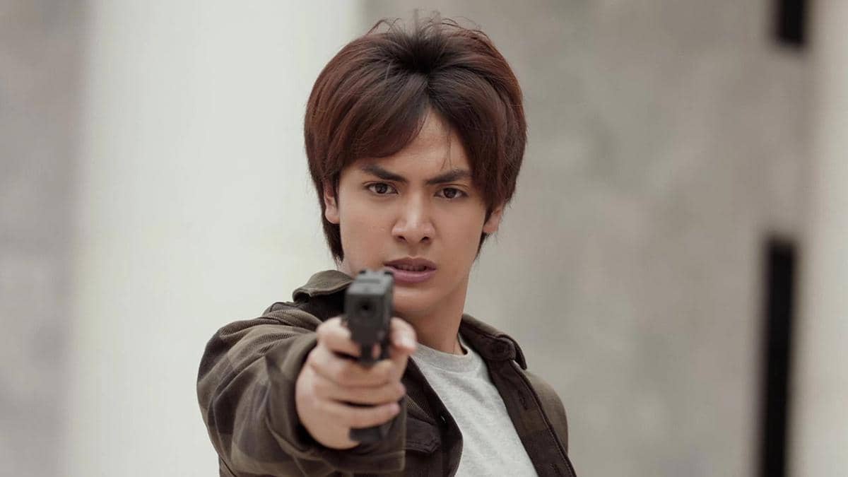 Seorang pria muda menodongkan pistol dengan ekspresi serius dalam cuplikan serial Mafia The Series: Guns & Freaks.