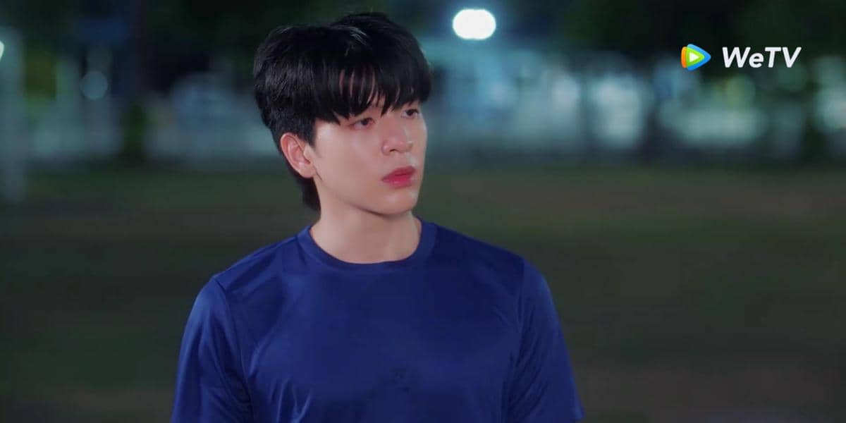 Seorang pria mengenakan kaus biru berdiri di luar ruangan pada malam hari dalam cuplikan serial Fourever You Part 2 di WeTV.