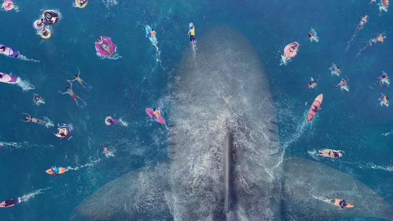 Pemandangan udara hiu raksasa mendekati sekelompok orang yang sedang berenang dan bermain pelampung di laut biru jernih.