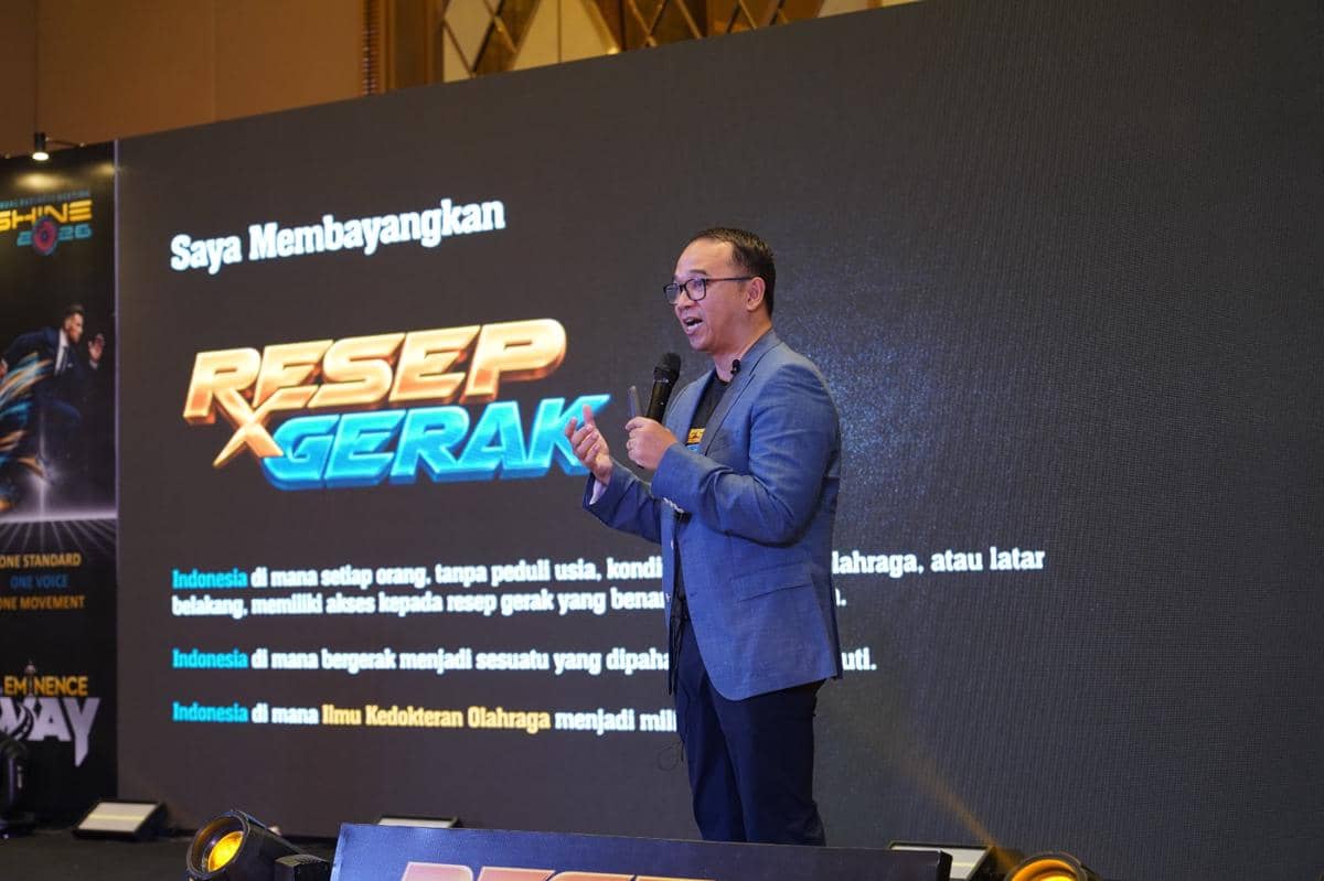 Seorang pria berbicara di atas panggung dengan mikrofon saat peluncuran resmi platform Resep Gerak ID di depan layar besar.