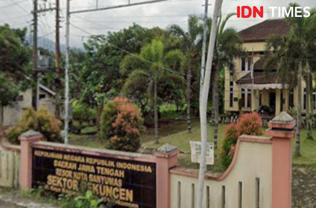 Tampak depan kantor Polsek Pekuncen di Banyumas, Jawa Tengah, dengan halaman hijau dan papan nama di depan pagar.