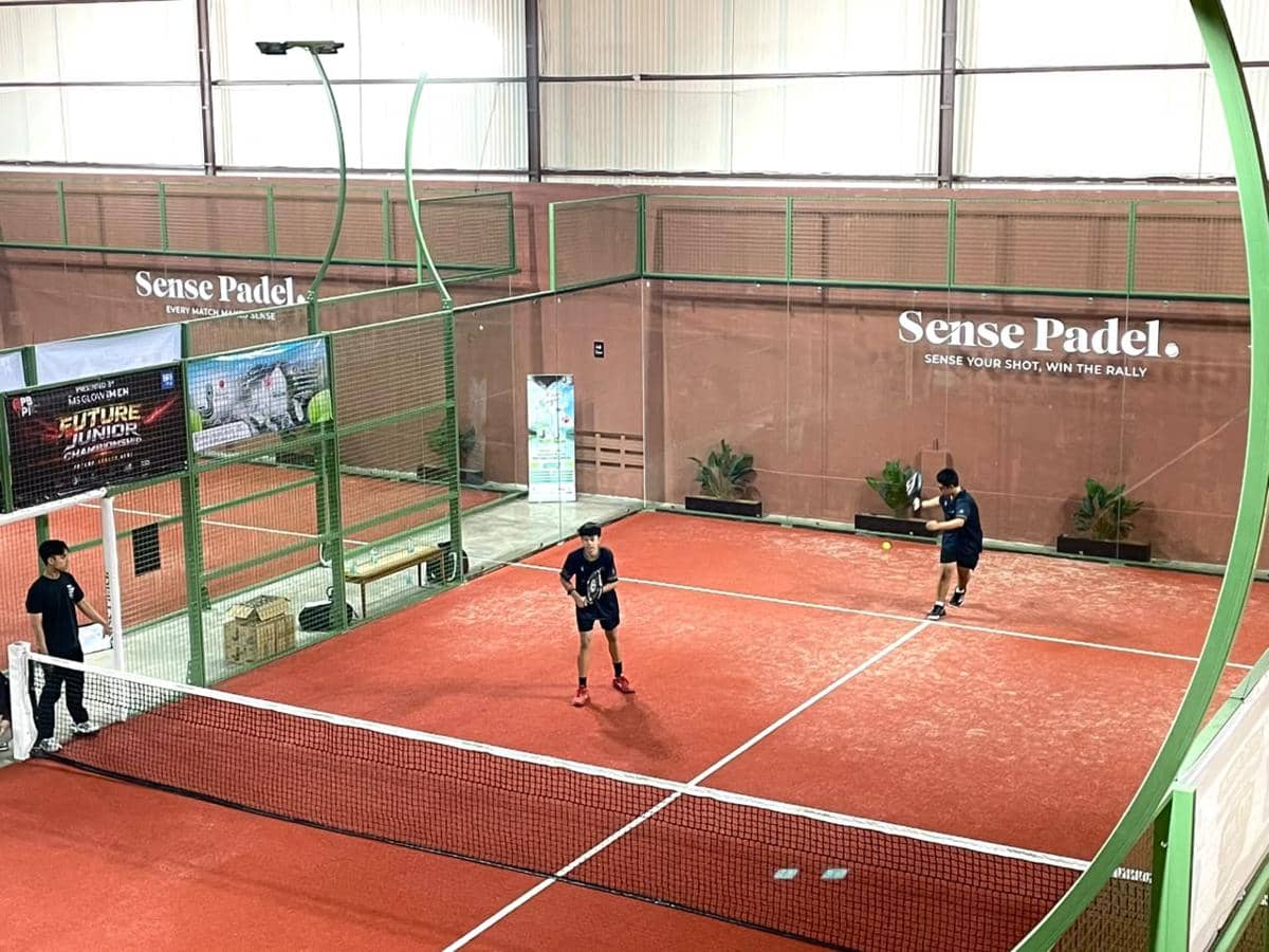 Dua pemain muda sedang bertanding padel di lapangan indoor berwarna merah dalam ajang MS Glow For Men Future Junior Championships di Jakarta.