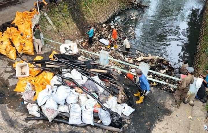 Petugas membersihkan tumpukan sampah dari Kali Sabi di Tangerang dengan karung besar berisi limbah untuk mencegah banjir.