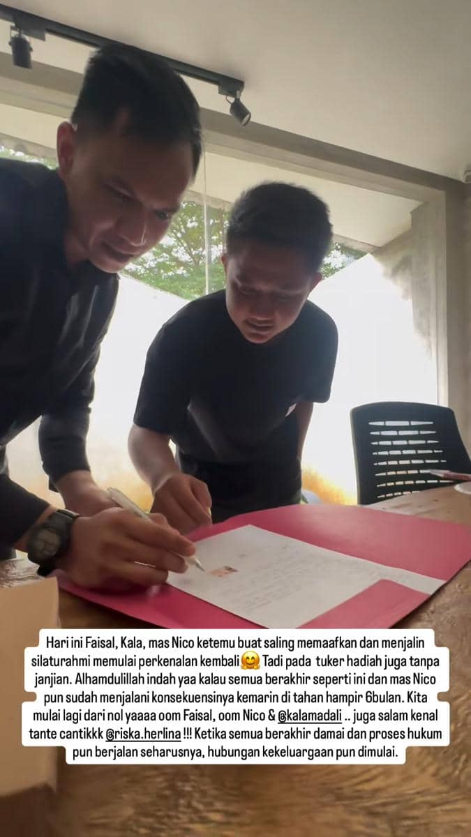 Dua pria mengenakan pakaian hitam sedang menandatangani dokumen di atas meja kayu dengan map merah di sebuah ruangan terang.
