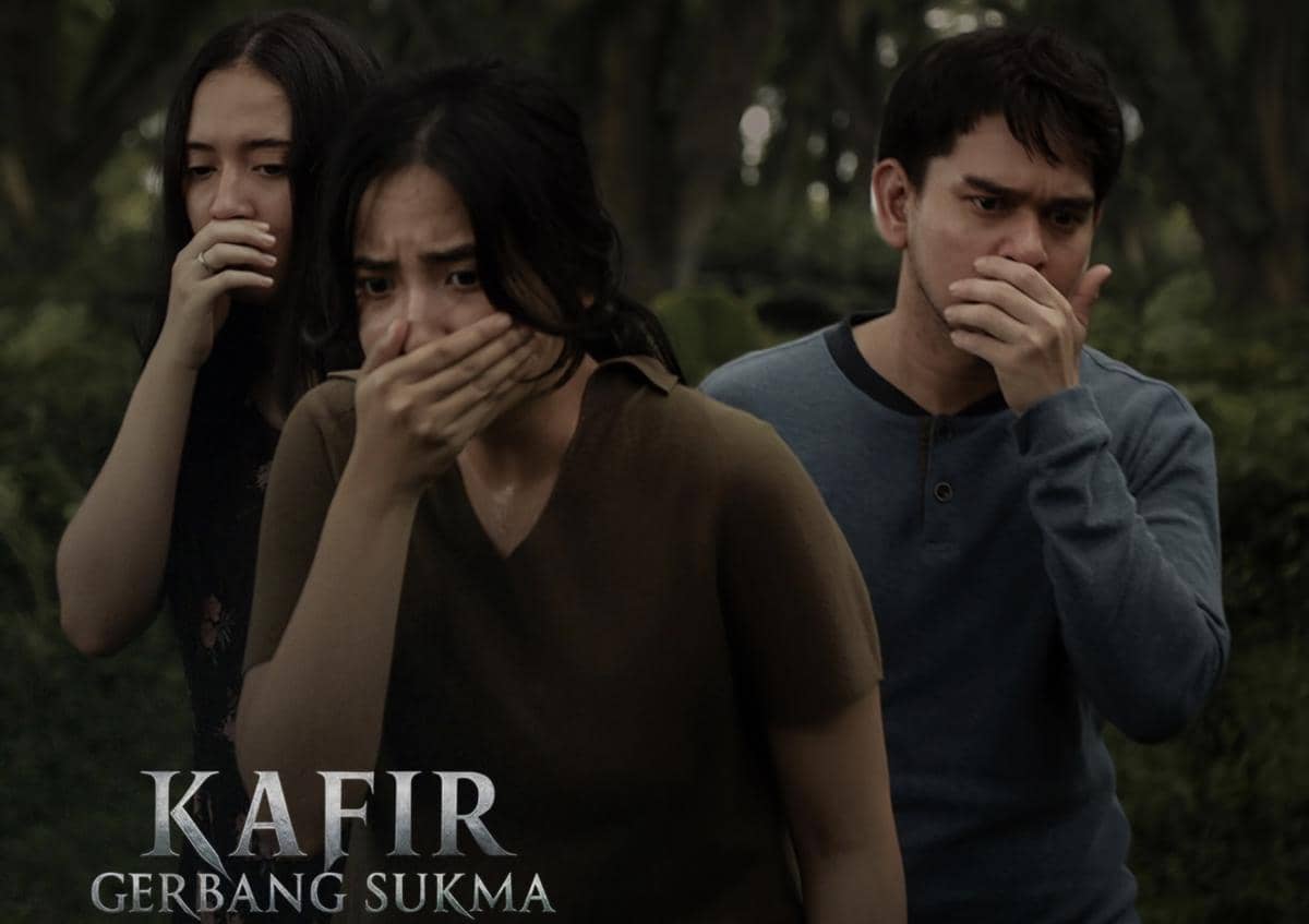 Tiga orang berdiri di luar ruangan dengan ekspresi ketakutan, menutup mulut mereka dalam suasana tegang dari film Kafir: Gerbang Sukma.