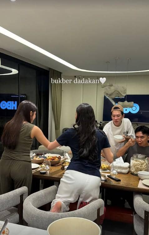 Beberapa orang berkumpul di ruang makan menikmati hidangan buka puasa bersama dengan suasana santai dan akrab.