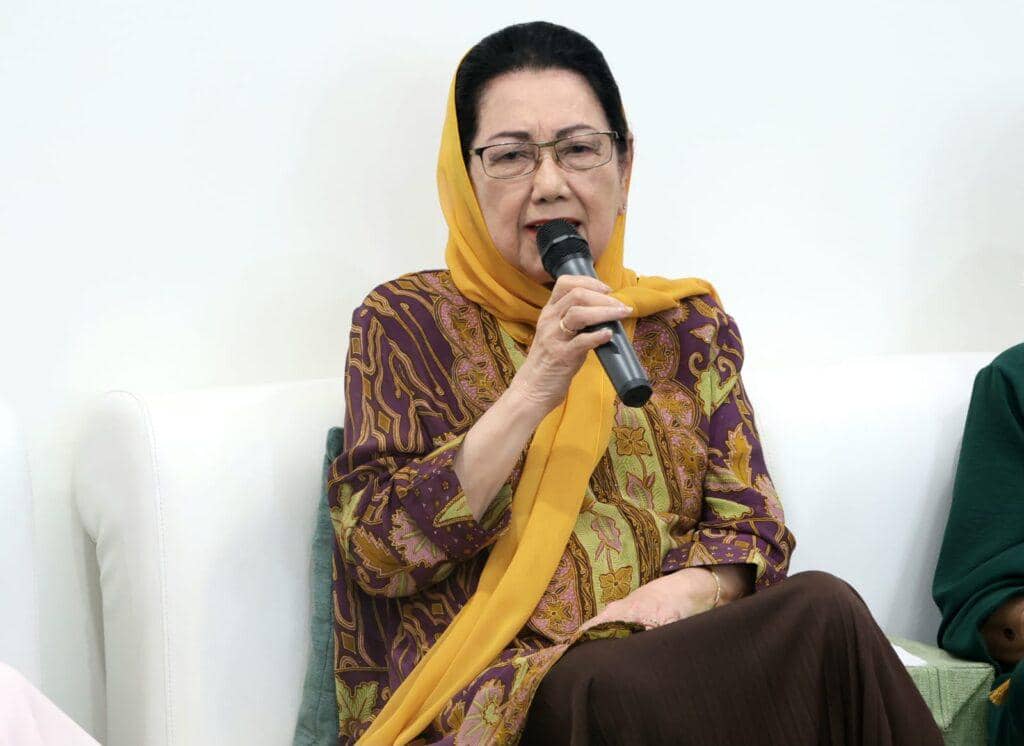 Seorang perempuan mengenakan kerudung kuning dan batik ungu berbicara menggunakan mikrofon saat acara haul yang digelar oleh KONI.