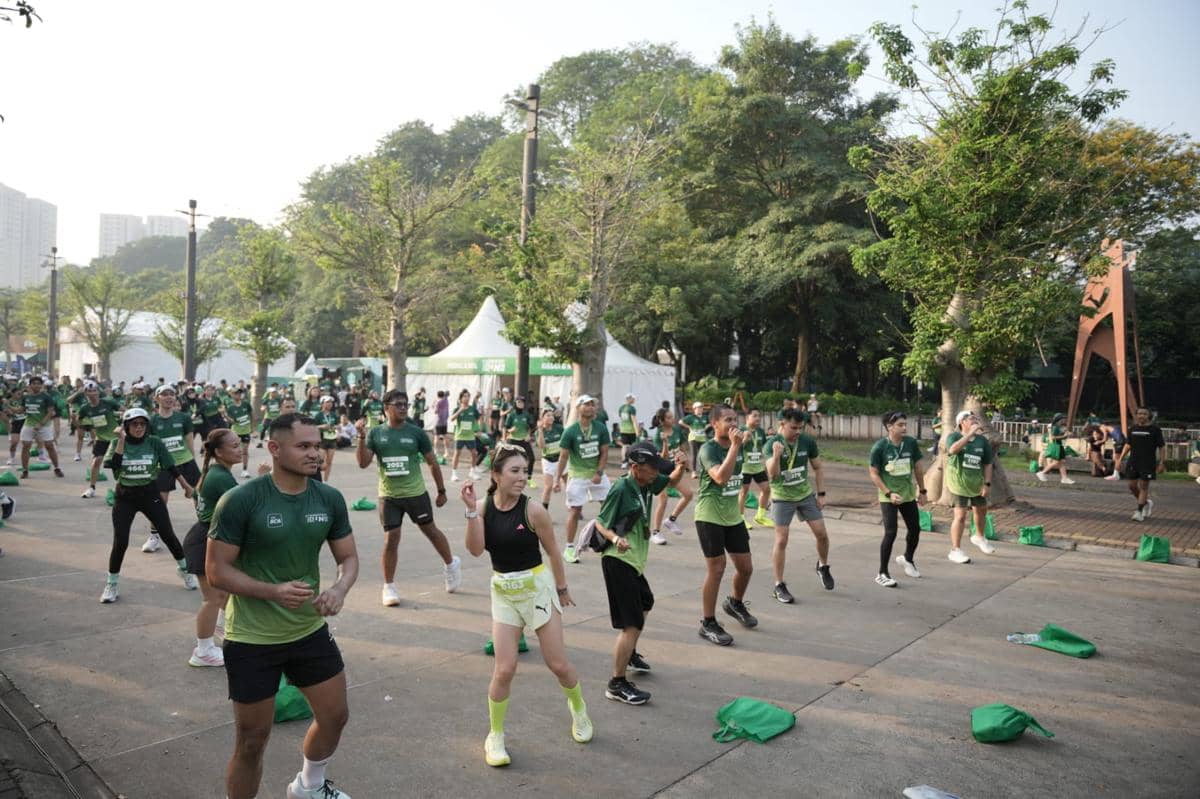Peserta Starbucks Run 2026 di Jakarta melakukan pemanasan bersama di area terbuka dengan mengenakan kaus hijau dan perlengkapan lari.