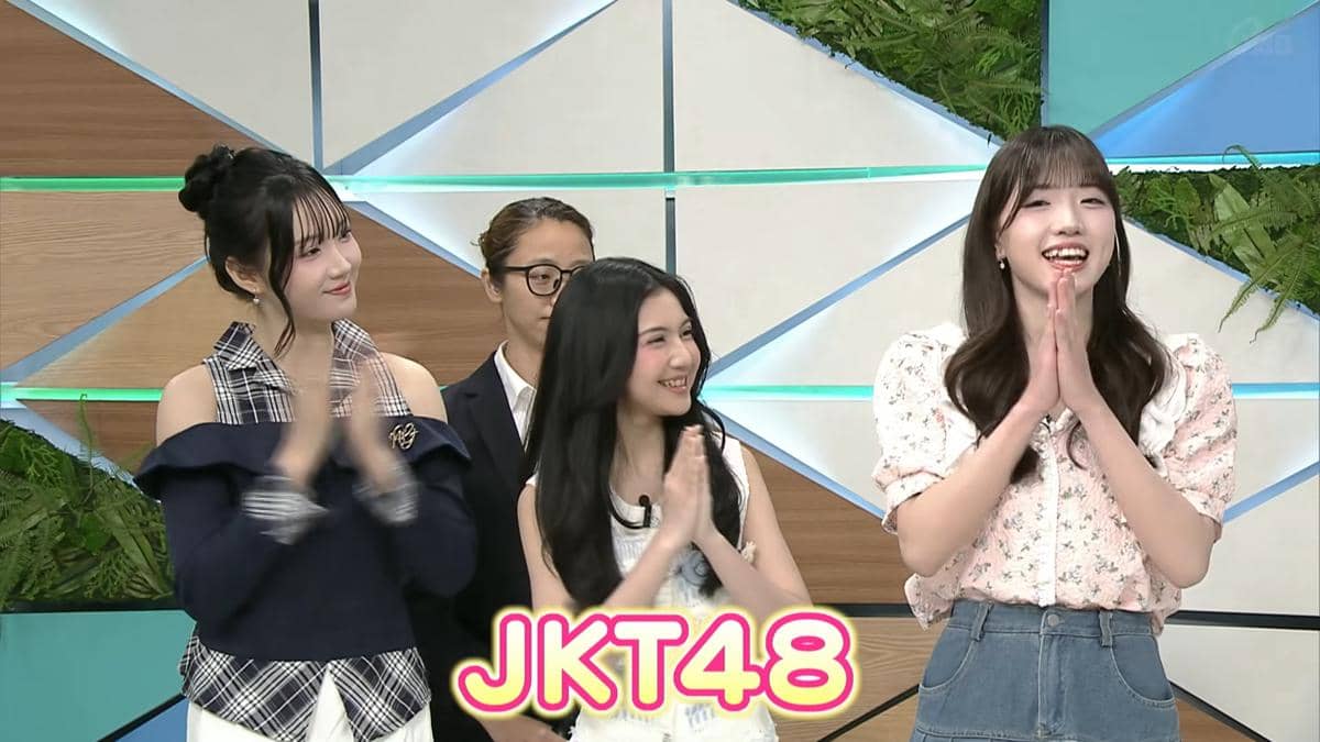 Tiga anggota JKT48 tersenyum dan bertepuk tangan saat tampil di acara televisi Jepang CATCHY dengan latar studio modern berwarna cerah.