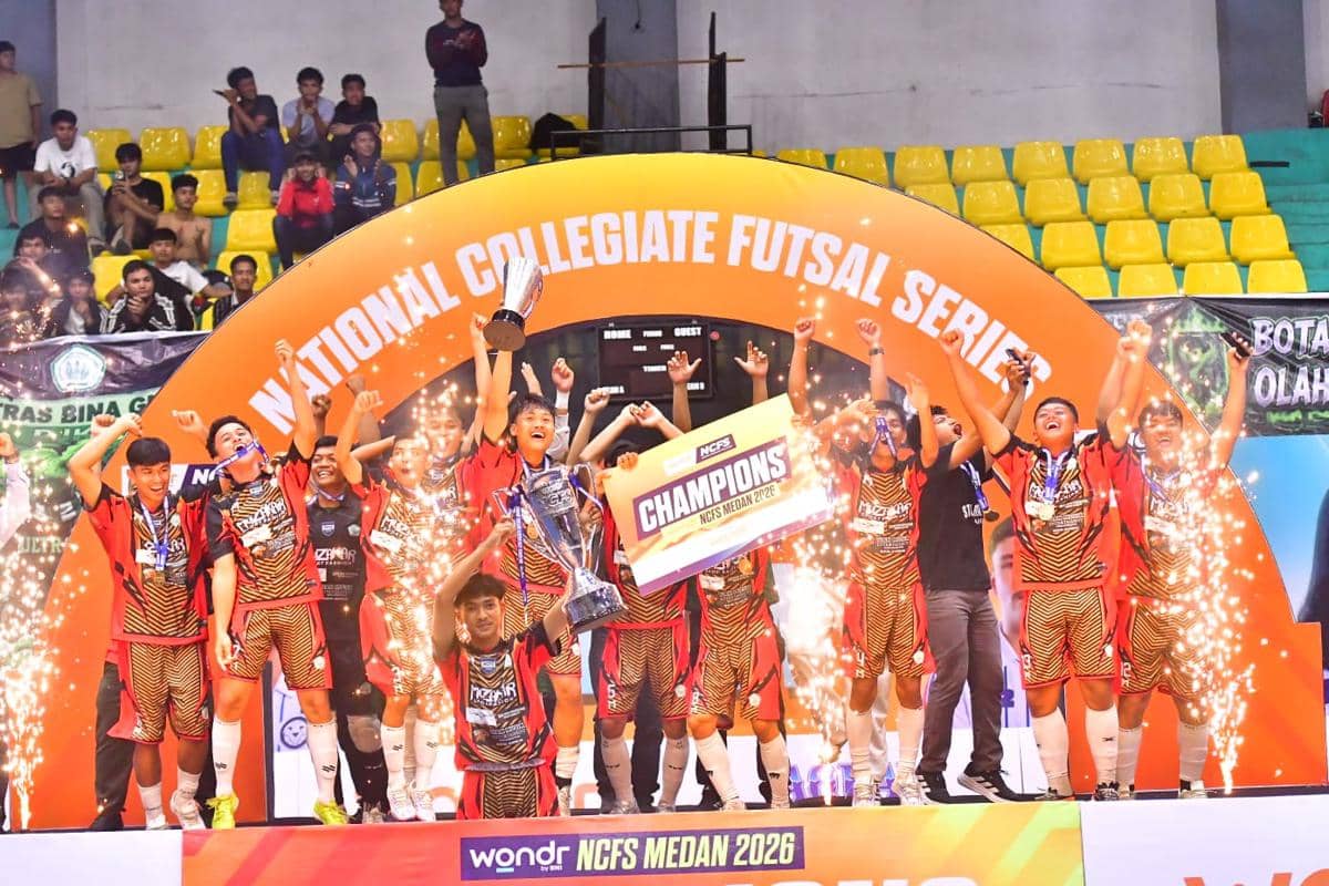Tim futsal STOK Bina Guna merayakan kemenangan di panggung juara NCFS Medan 2026 dengan trofi dan pesta kembang api di dalam gedung olahraga.