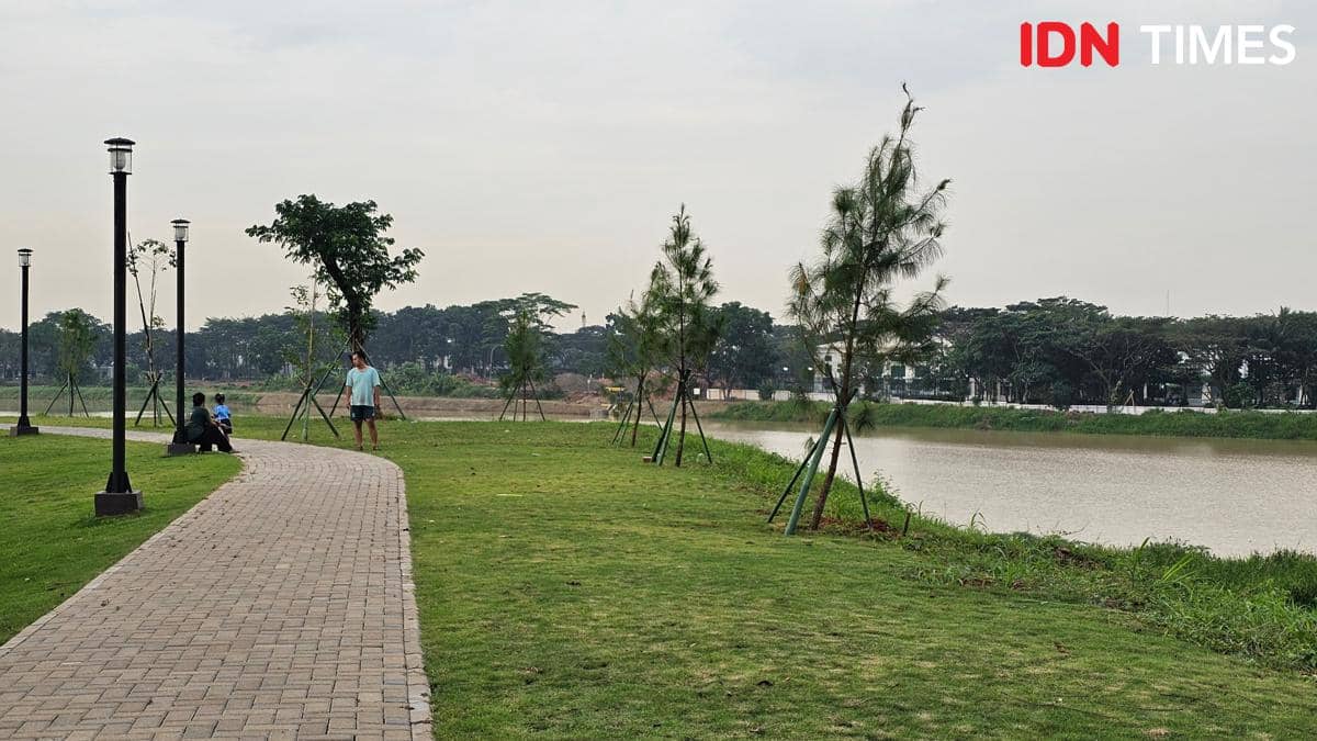 Jalur jogging di tepi Danau Cihuni Tangerang dengan pepohonan muda, lampu taman, dan beberapa orang menikmati suasana sore.