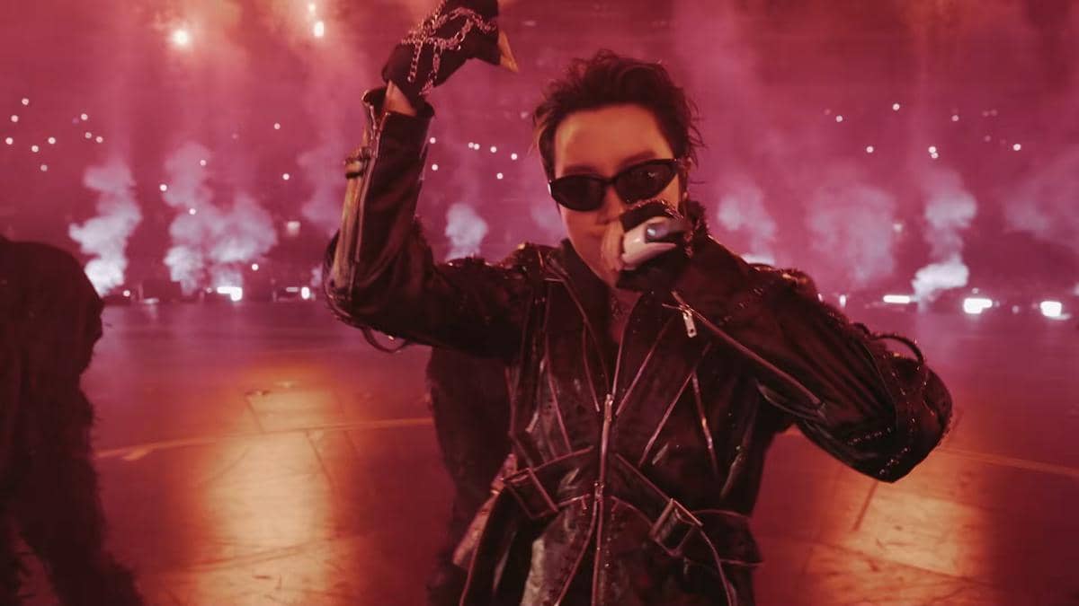Seorang anggota BTS tampil energik di panggung American Music Awards 2026 dengan pencahayaan merah dan efek asap dramatis.