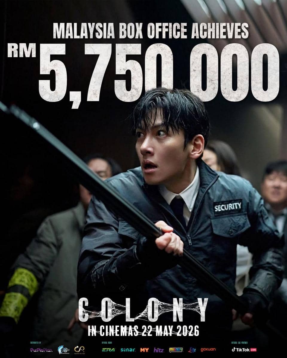 Seorang pria mengenakan seragam keamanan memegang tongkat di adegan film Korea Colony dengan tulisan pencapaian box office Malaysia RM5.750.000.