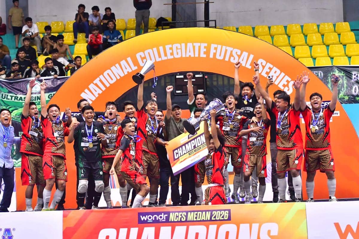 Tim futsal STOK Bina Guna merayakan kemenangan dengan mengangkat trofi dan papan juara pada ajang NCFS Medan 2026 di lapangan indoor.
