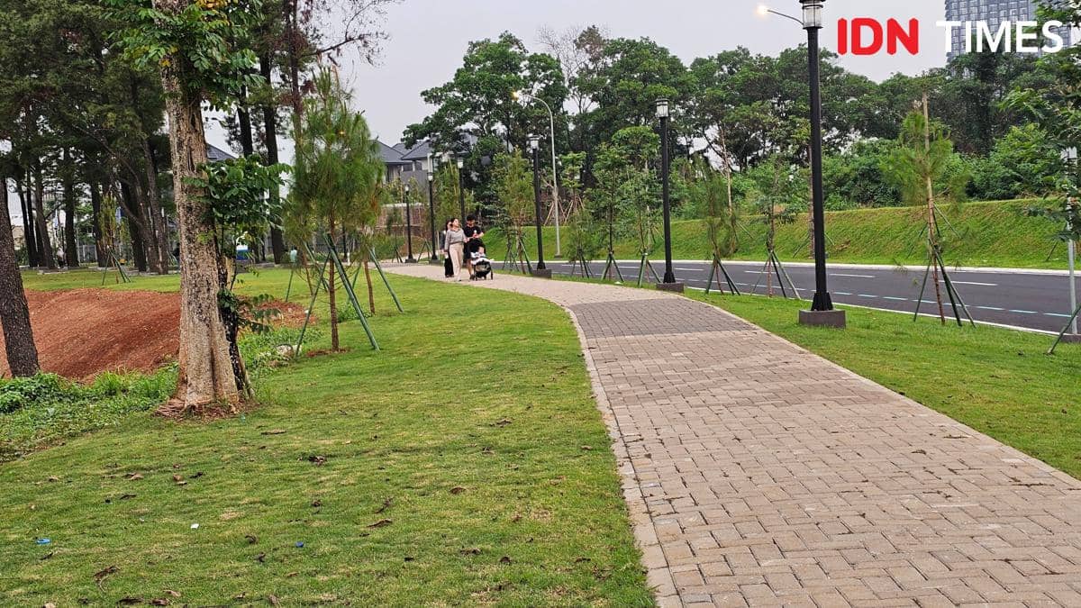 Jalur pedestrian di Danau Cihuni Tangerang dengan pepohonan hijau dan beberapa orang berjalan santai di sore hari.