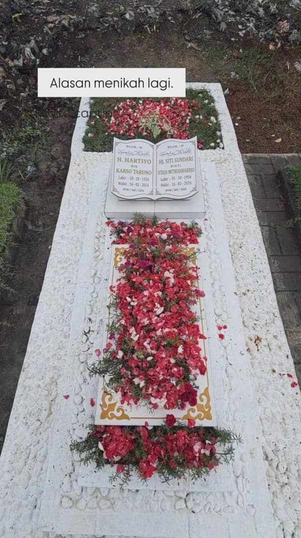 Makam pasangan suami istri dengan batu nisan berukir nama dan tanggal lahir serta wafat, dihiasi taburan bunga merah dan putih.