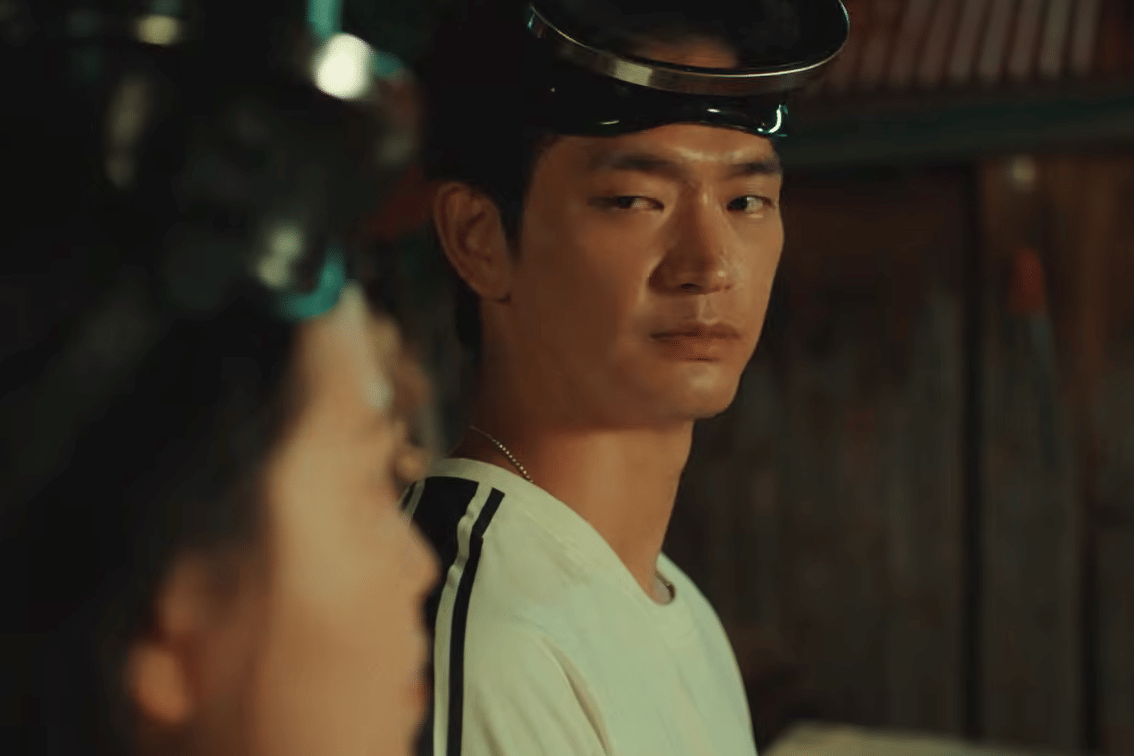 Seorang pria mengenakan pelindung kepala menatap seseorang di depannya dalam adegan drama Azure Spring dengan pencahayaan hangat.