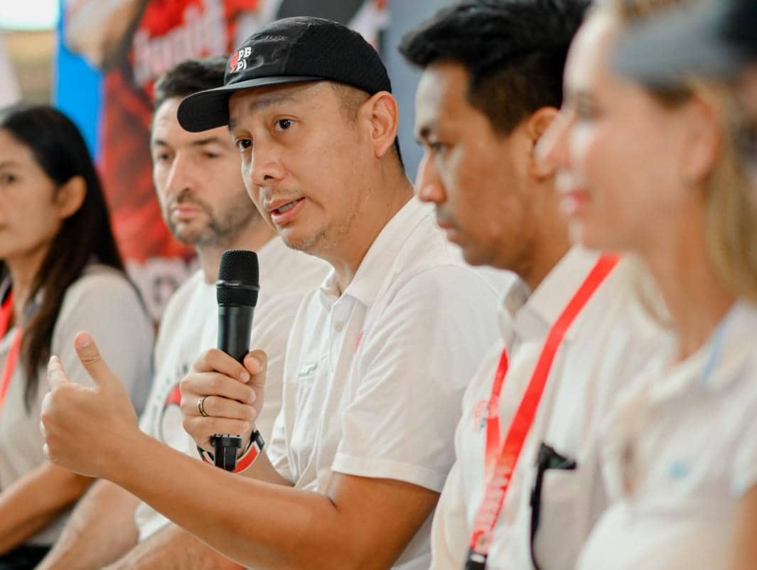 Seorang pria berbicara memegang mikrofon saat konferensi pers bersama beberapa orang lainnya mengenakan pakaian putih.