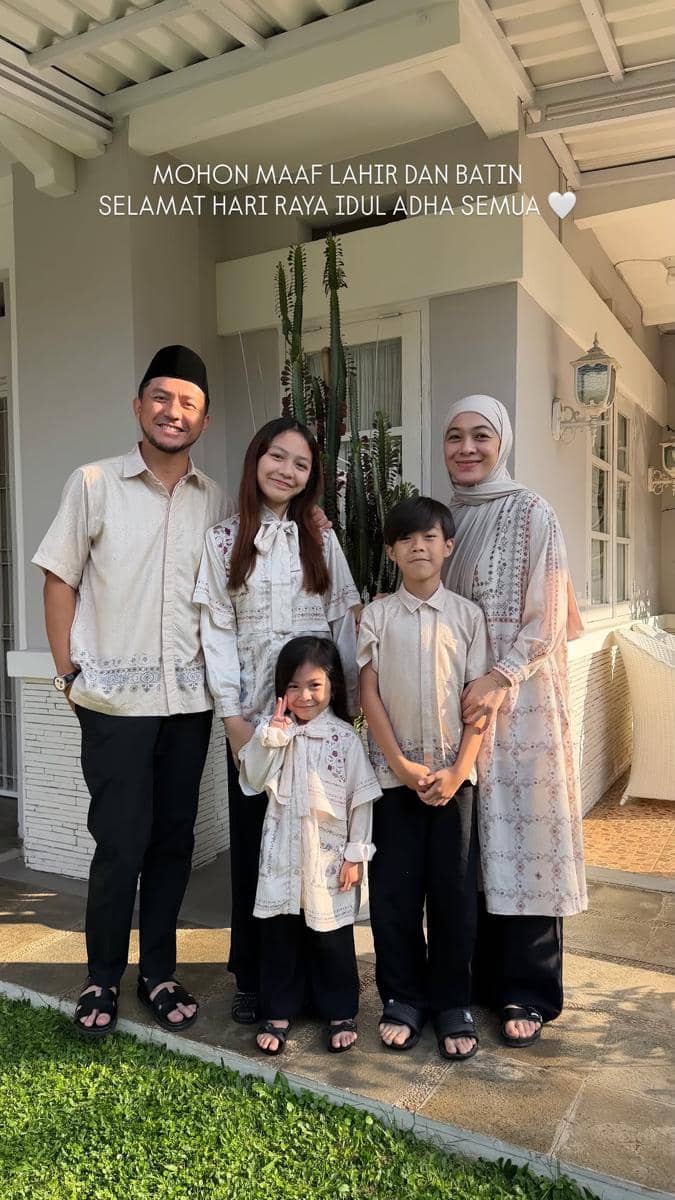 Sebuah keluarga berpose bersama di depan rumah mengenakan busana senada berwarna krem untuk merayakan Idul Adha.