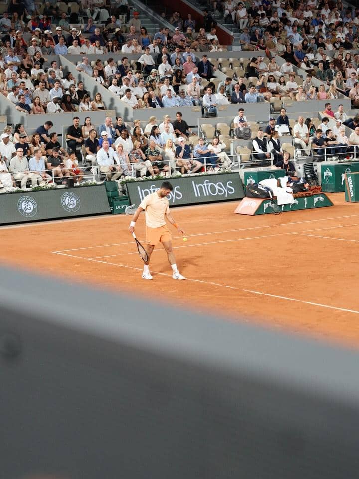 Seorang petenis sedang bertanding di lapangan tanah liat dengan penonton memenuhi tribun stadion tenis di Paris.