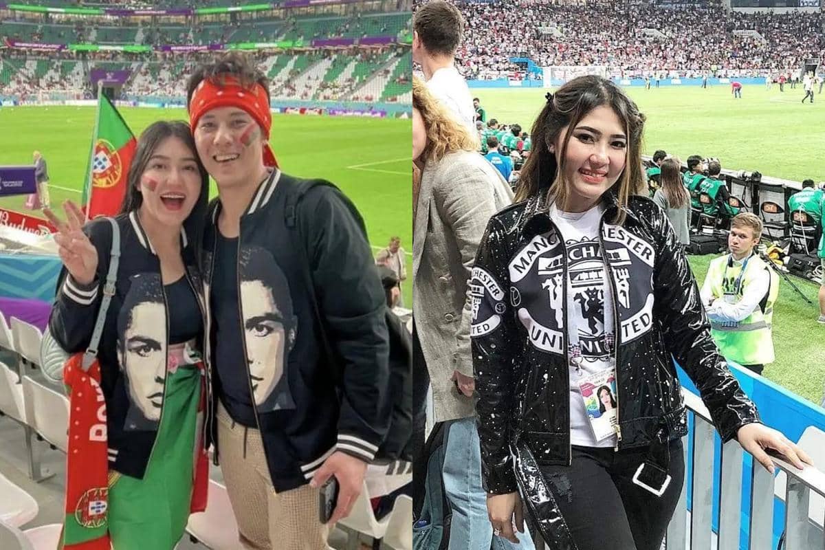 Seorang perempuan berpose di stadion sepak bola saat menonton Piala Dunia, mengenakan jaket bergambar dan atribut tim sepak bola.