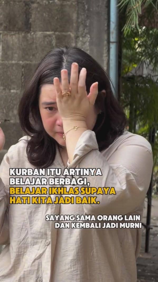 Seorang perempuan mengenakan kemeja krem tampak menyeka air mata sambil menutup sebagian wajahnya dengan tangan di luar ruangan.