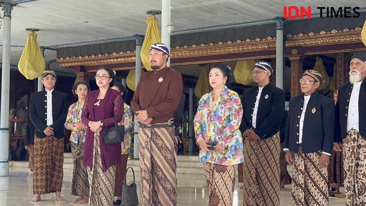 Sejumlah orang mengenakan busana adat Jawa berdiri di pendapa keraton saat menyaksikan kirab Grebeg Besar di Surakarta.