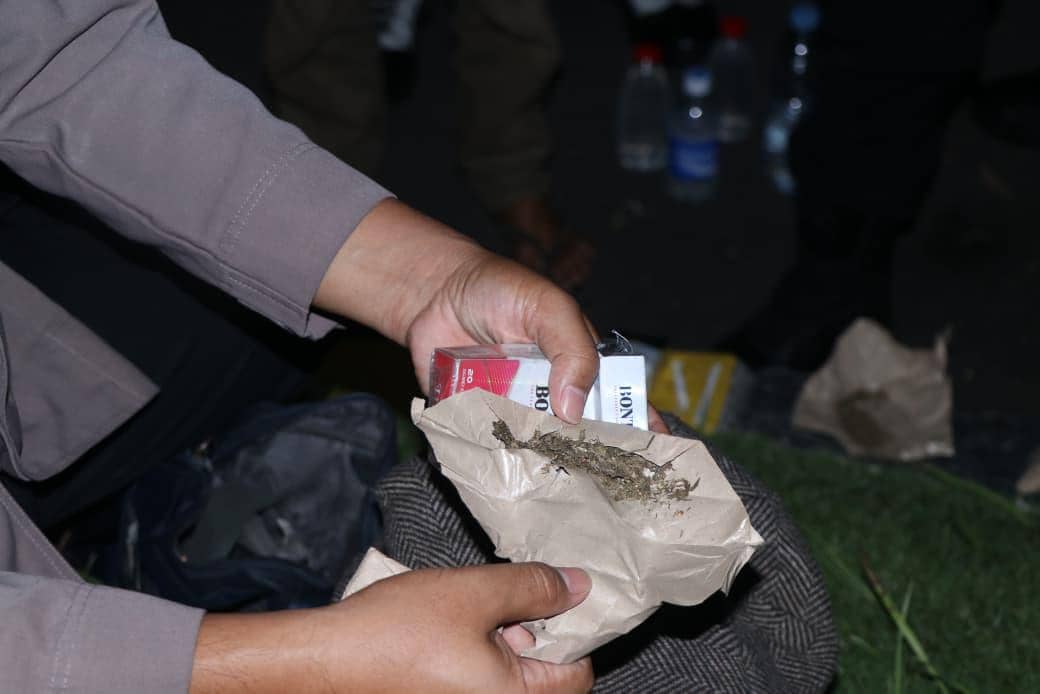Petugas memegang bungkus kertas berisi ganja kering dan sebungkus rokok saat pengungkapan kasus peredaran narkotika di Tangerang.