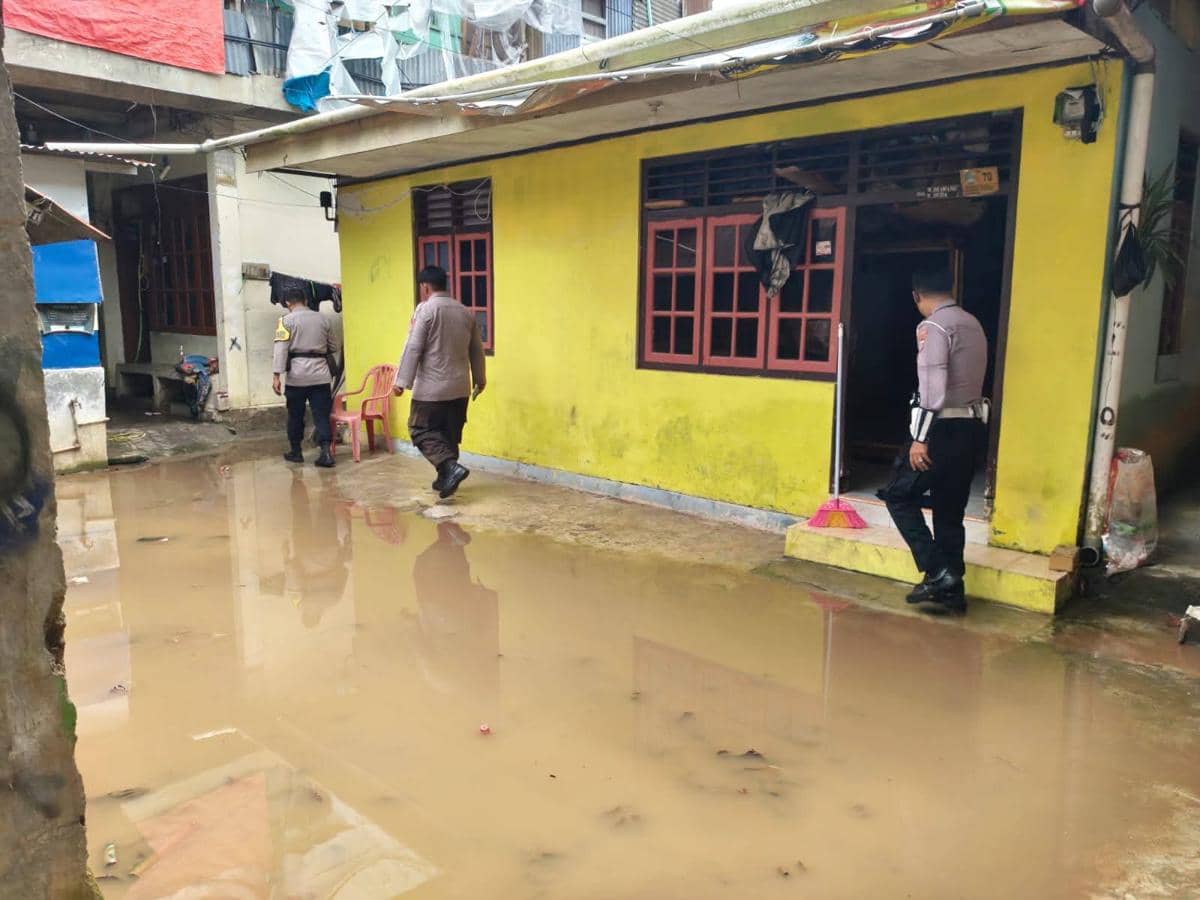 Beberapa petugas polisi memeriksa area rumah berwarna kuning yang tergenang air sisa banjir di Kelurahan Komo Luar, Manado.