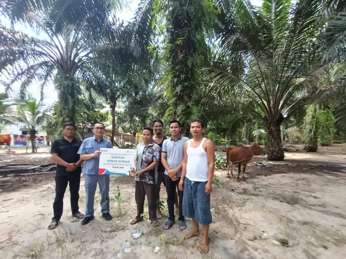 Beberapa orang berfoto bersama di area perkebunan sawit saat penyerahan bantuan hewan kurban dari PT Indonesia Asahan Aluminium.