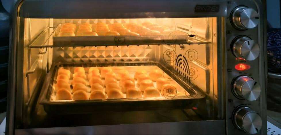 Pisang bolen dipanggang di atas loyang dalam oven dapur hingga matang untuk disajikan sebagai kudapan hangat.